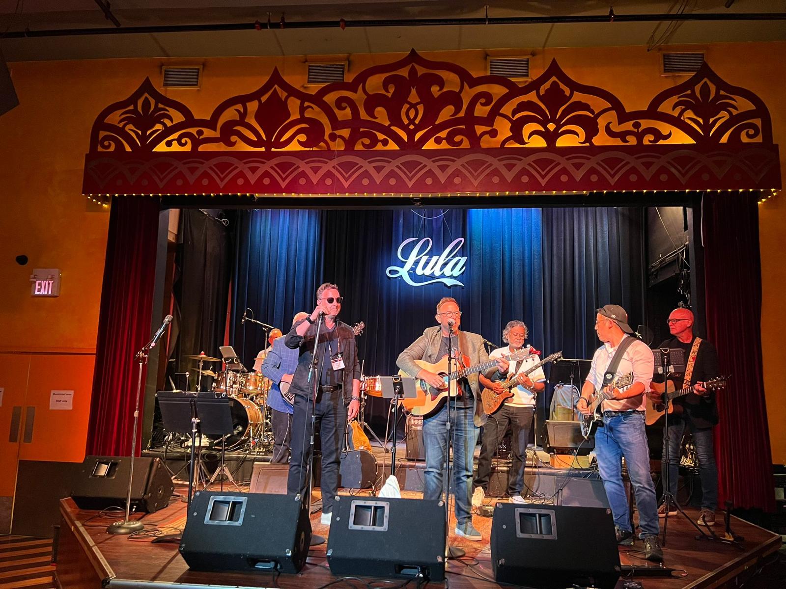 band members playing guitar and drums in rehearsal room